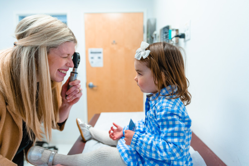 a pediatrician looking at the eyes of a young girl